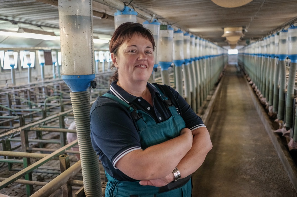 A woman standing in a barn with her arms crossed.